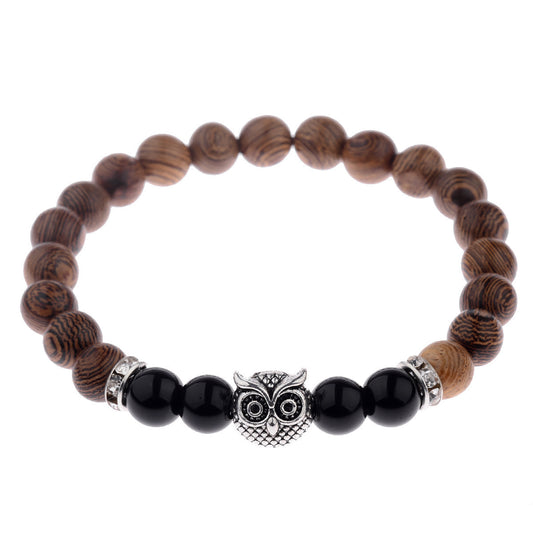 Close-up of owl-engraved frosted stone beads on wood grain bracelet.