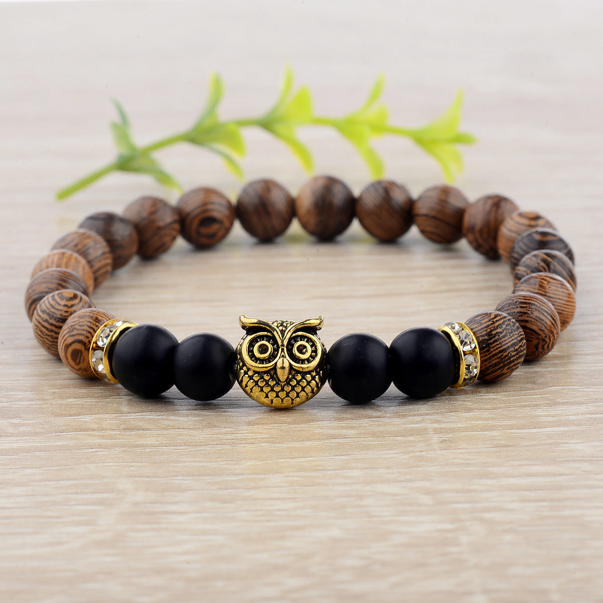 Close-up of owl-engraved frosted stone beads on wood grain bracelet.